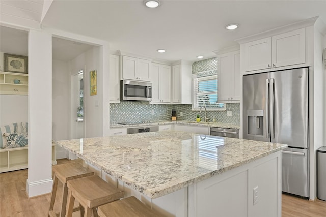 kitchen with light wood-style floors, white cabinets, appliances with stainless steel finishes, and decorative backsplash