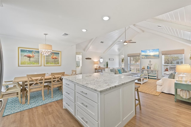 kitchen featuring light wood-type flooring, white cabinetry, a kitchen island, vaulted ceiling with beams, and open floor plan