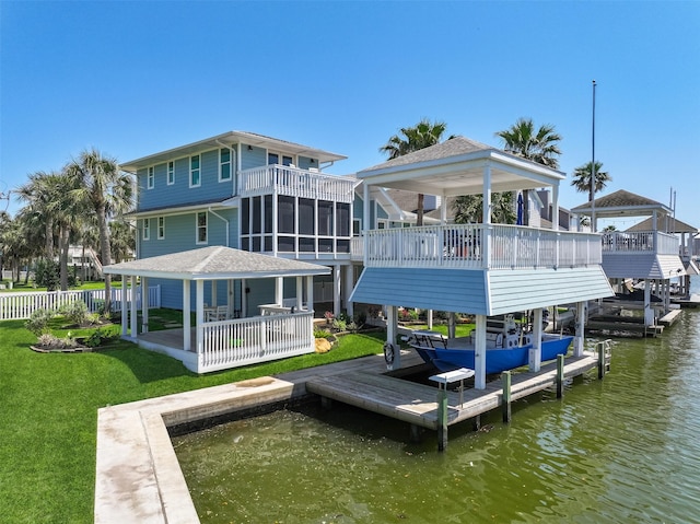 dock area featuring boat lift, a lawn, fence, and a water view