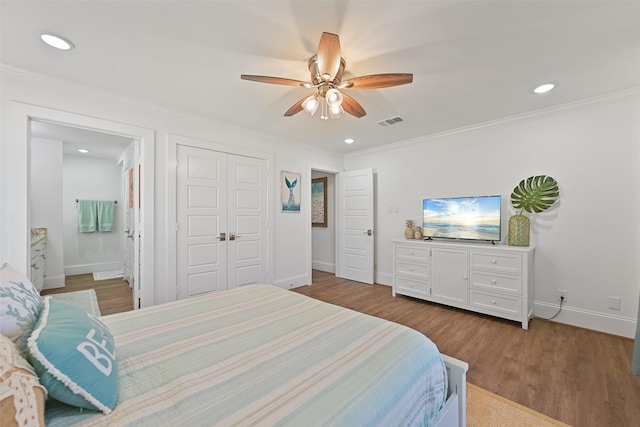 bedroom featuring ornamental molding, visible vents, baseboards, and wood finished floors