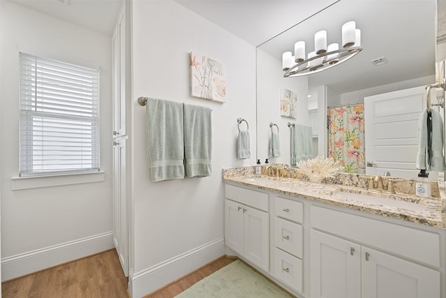 full bathroom with visible vents, baseboards, a sink, and wood finished floors