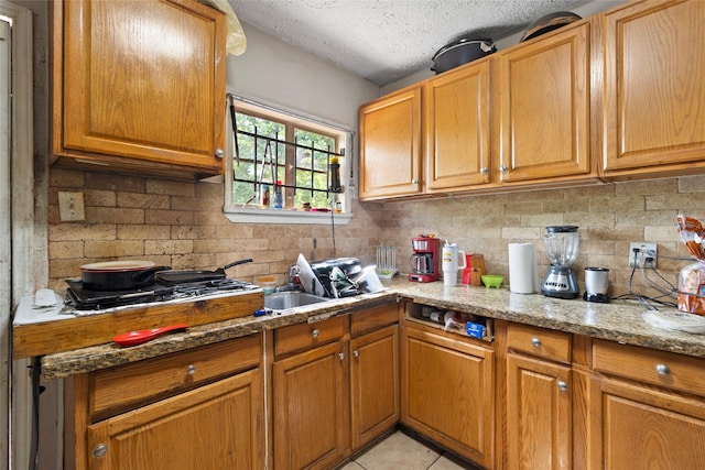 6109 Wayland St, Houston, TX 77021 - kitchen featuring a textured ceiling, tasteful backsplash, light stone counters, and brown cabinets