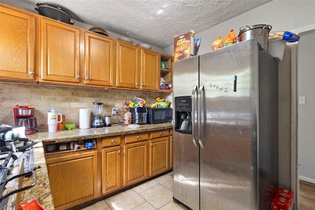 6109 Wayland St, Houston, TX 77021 - kitchen featuring stainless steel fridge, tasteful backsplash, a textured ceiling, brown cabinetry, and black microwave