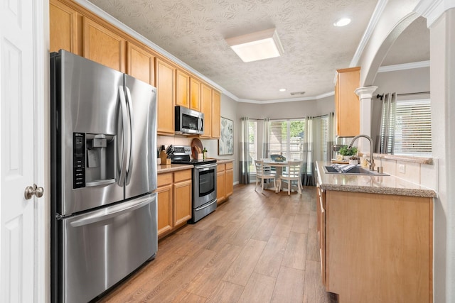 11926 Brightwood Dr, Montgomery, TX 77356 - kitchen featuring crown molding, stainless steel appliances, arched walkways, light wood finished floors, and a sink
