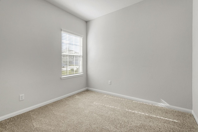 spare room with baseboards and light colored carpet