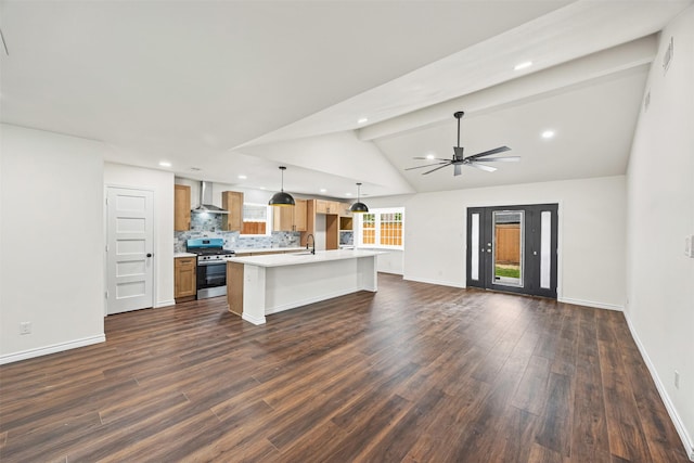 kitchen featuring light countertops, wall chimney range hood, gas stove, open floor plan, and ceiling fan