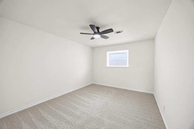 spare room featuring baseboards, a ceiling fan, visible vents, and light colored carpet