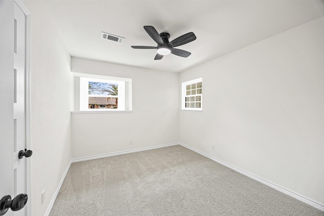 carpeted spare room featuring baseboards, a ceiling fan, and visible vents