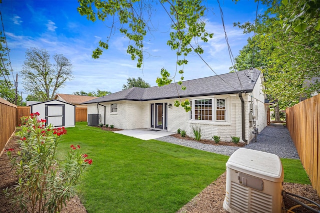 rear view of house featuring a fenced backyard, a storage unit, brick siding, and central AC