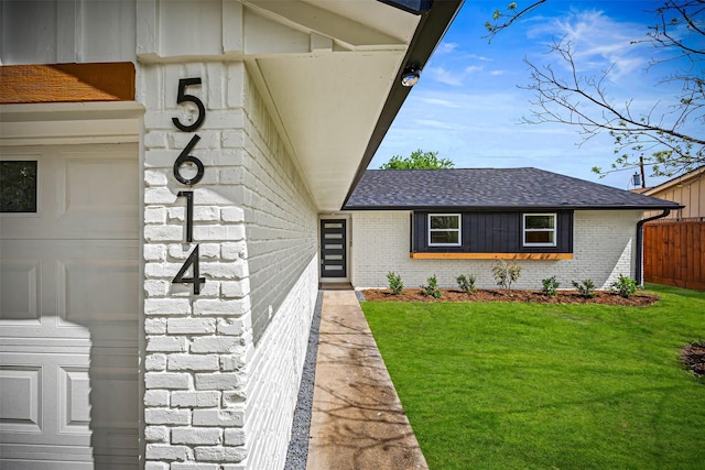 property entrance featuring brick siding, a lawn, and roof with shingles