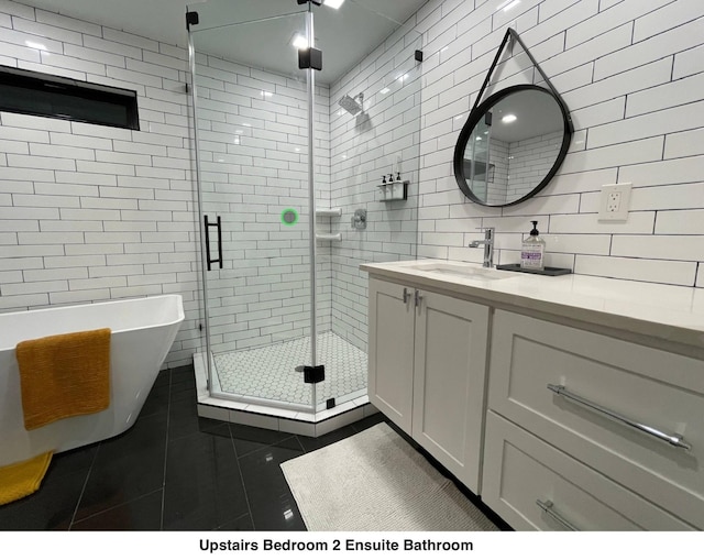 full bathroom featuring tile patterned flooring, vanity, tile walls, a freestanding tub, and a stall shower