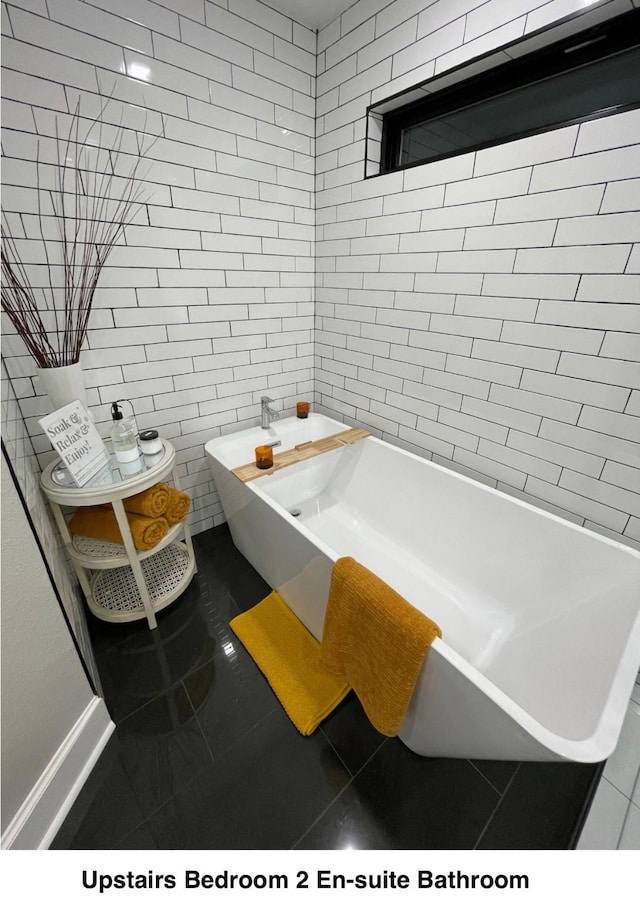 bathroom with tile patterned floors, baseboards, and a bathing tub