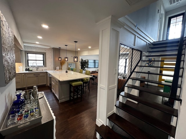 kitchen with a peninsula, a kitchen breakfast bar, a sink, recessed lighting, and dark wood-type flooring