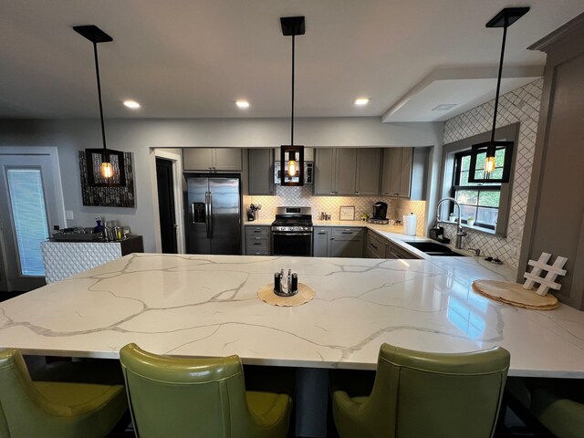 kitchen featuring a sink, gray cabinets, backsplash, a peninsula, and appliances with stainless steel finishes