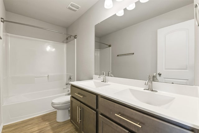 full bathroom featuring toilet, wood finished floors, double vanity, and shower / bath combination