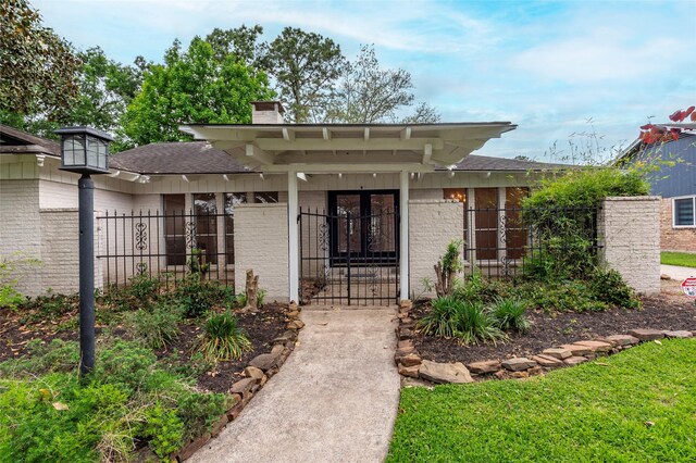 doorway to property featuring a gate, brick siding, a chimney, and fence