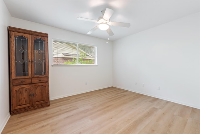 empty room featuring light wood-type flooring, a ceiling fan, and baseboards