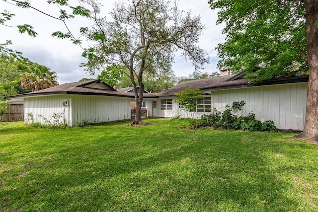 rear view of property featuring fence, a lawn, and a chimney