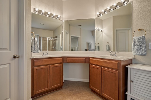 bathroom with tile patterned flooring, a stall shower, double vanity, and a textured wall