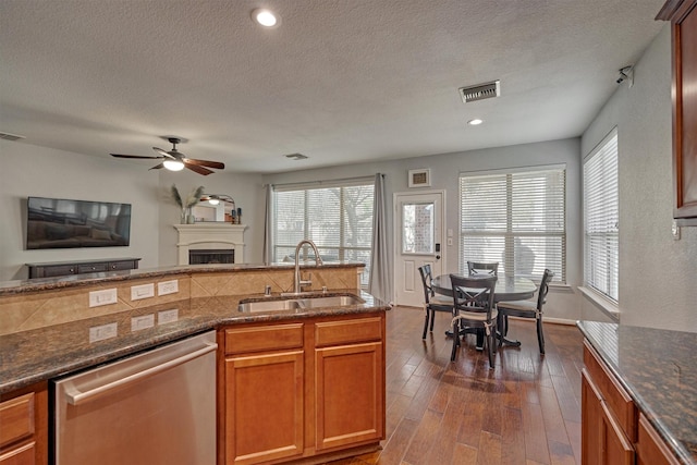 kitchen with a sink, dishwasher, plenty of natural light, a fireplace, and a textured ceiling