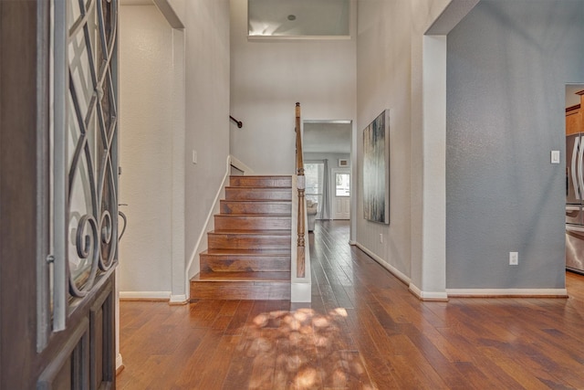 entrance foyer featuring hardwood / wood-style flooring, stairway, baseboards, and a high ceiling