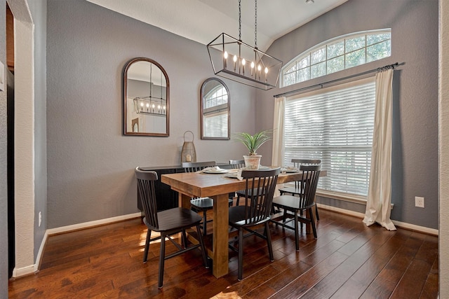 dining area featuring dark wood-style flooring, baseboards, a chandelier, vaulted ceiling, and a textured wall