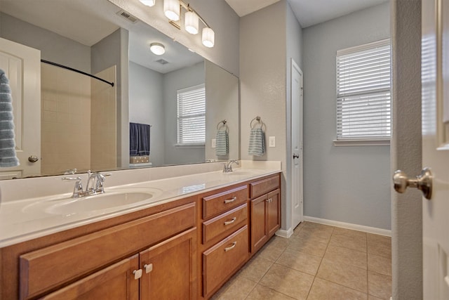 bathroom with tile patterned flooring, double vanity, baseboards, and a shower