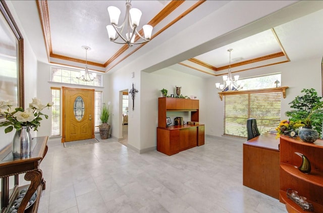 foyer entrance featuring a notable chandelier, a tray ceiling, and crown molding