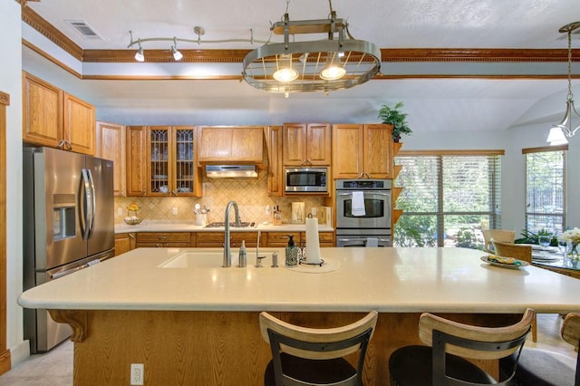 24501 Sable Creek Ct, Porter, TX 77365 - kitchen with appliances with stainless steel finishes, brown cabinetry, light countertops, and under cabinet range hood