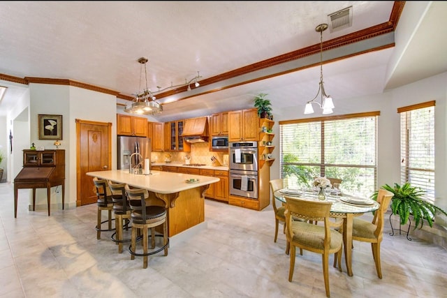 kitchen featuring visible vents, light countertops, appliances with stainless steel finishes, premium range hood, and brown cabinets
