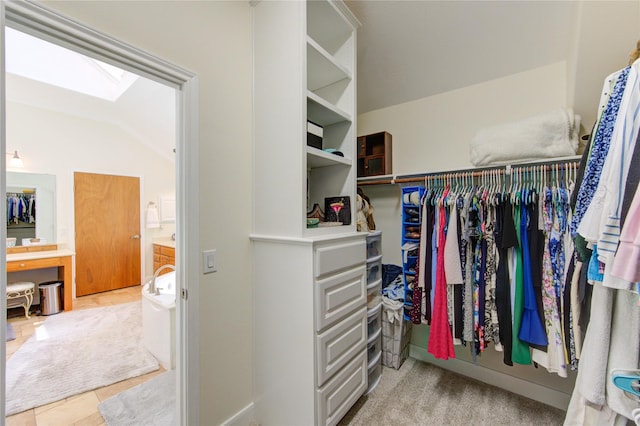 spacious closet featuring tile patterned floors and lofted ceiling with skylight