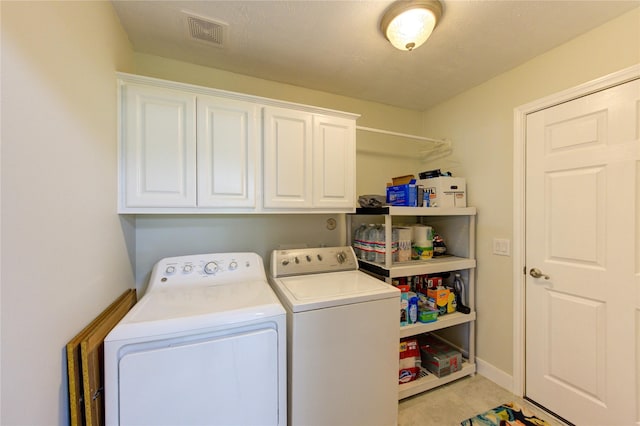 washroom featuring separate washer and dryer, visible vents, and cabinet space