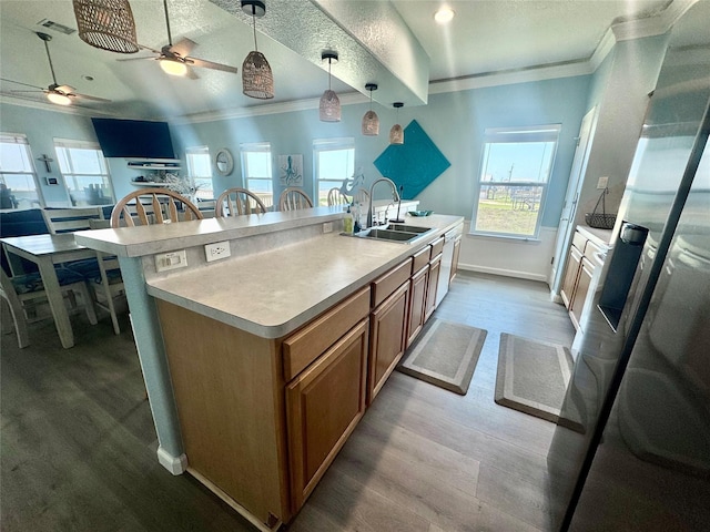101 Saltgrass Ave, Surfside Beach, TX 77541 - kitchen featuring a sink, ceiling fan, crown molding, brown cabinetry, and wood finished floors