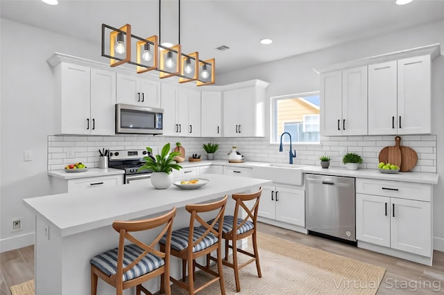 2015 Brackenridge St Unit A, Houston, TX 77026 - kitchen featuring appliances with stainless steel finishes, light wood-style floors, a kitchen bar, white cabinetry, and recessed lighting