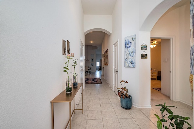 5819 Southern Rose Ln, Rosenberg, TX 77469 - corridor featuring arched walkways, light tile patterned floors, a towering ceiling, and baseboards