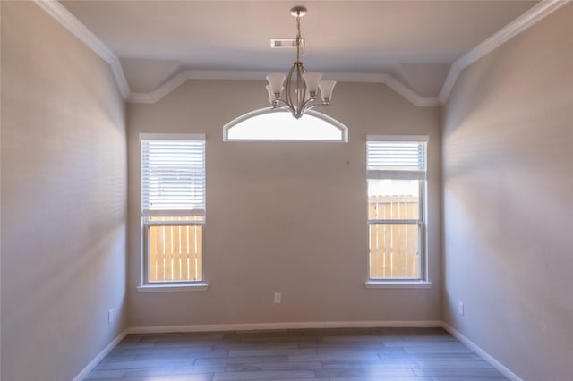spare room featuring a chandelier, crown molding, and plenty of natural light