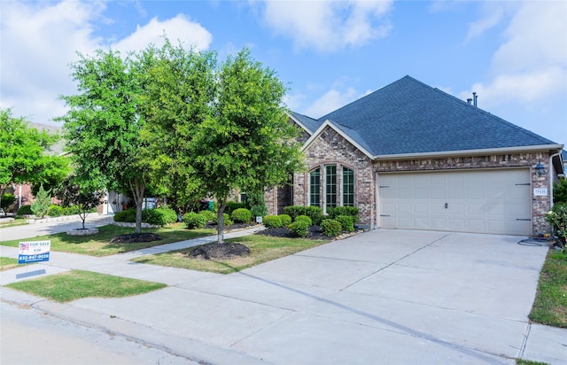 view of front of house with concrete driveway, a shingled roof, brick siding, and an attached garage