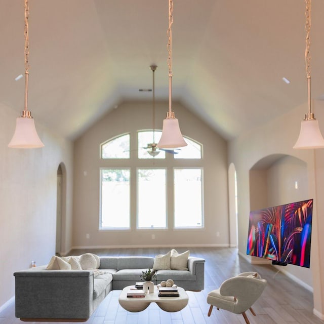 living room with arched walkways, wood finished floors, baseboards, and lofted ceiling