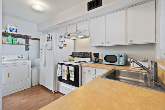 kitchen with wood finished floors, washer and dryer, white appliances, under cabinet range hood, and a sink