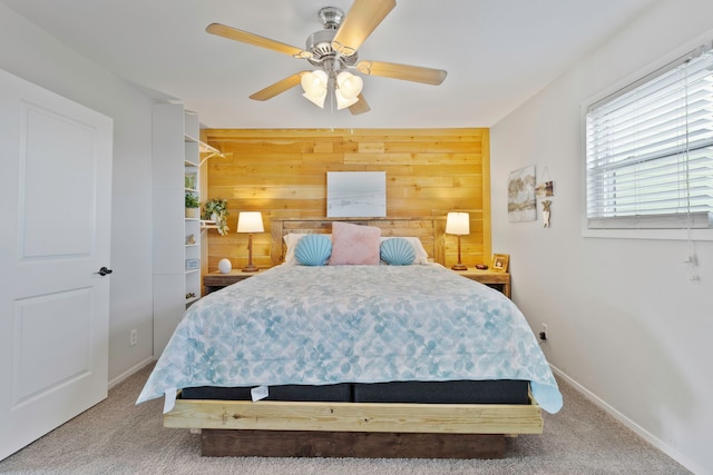 carpeted bedroom with baseboards, ceiling fan, and wood walls