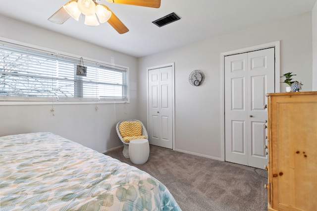 carpeted bedroom featuring baseboards, multiple closets, ceiling fan, and visible vents