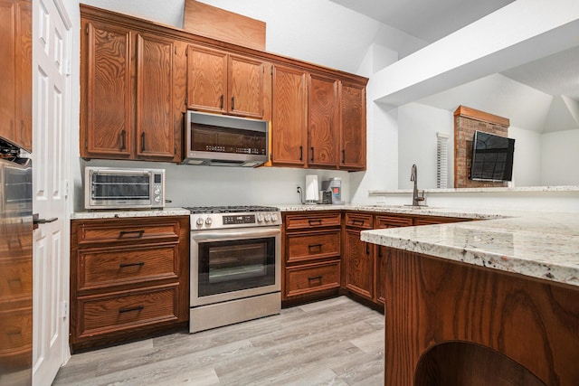 39 Alexander Ct, Angleton, TX 77515 - kitchen with stainless steel appliances, light stone counters, light wood-style flooring, a sink, and brown cabinets