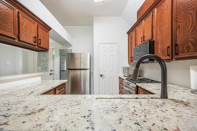 39 Alexander Ct, Angleton, TX 77515 - kitchen featuring stainless steel appliances, light stone counters, lofted ceiling, and brown cabinets