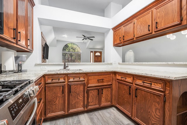 39 Alexander Ct, Angleton, TX 77515 - kitchen featuring a sink, a ceiling fan, light wood-style floors, brown cabinets, and light stone countertops