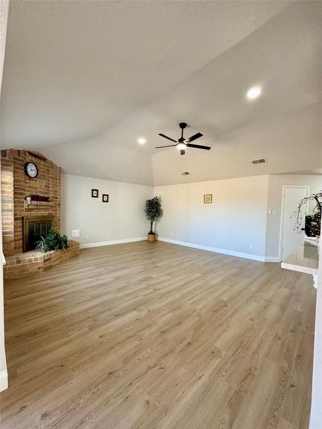 unfurnished living room with baseboards, vaulted ceiling, visible vents, and light wood-type flooring