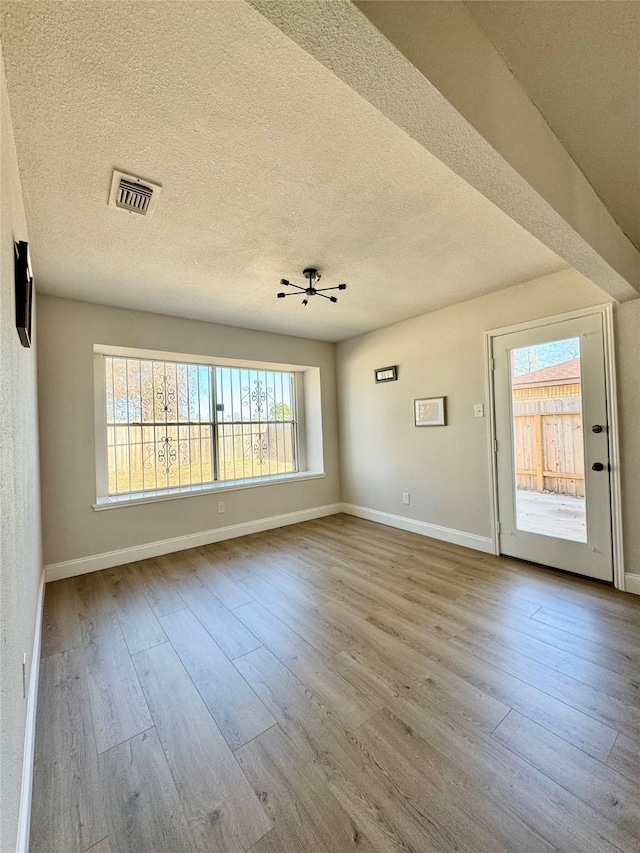 interior space with visible vents, baseboards, wood finished floors, and a textured ceiling