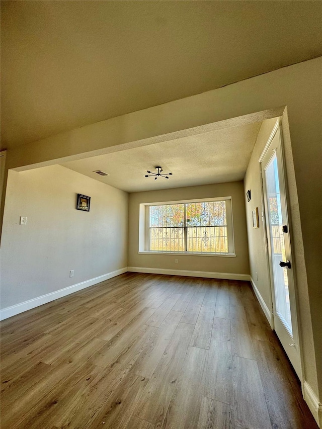 empty room featuring visible vents, baseboards, and dark wood finished floors
