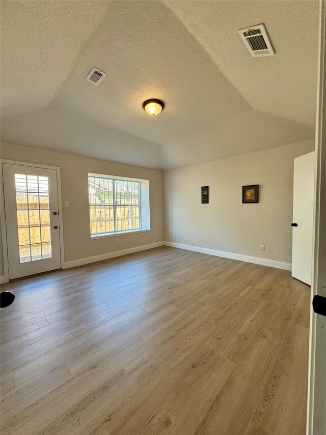 unfurnished room with wood finished floors, visible vents, and a textured ceiling