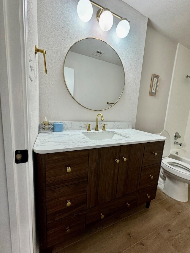 bathroom featuring wood finished floors, visible vents, toilet, vanity, and shower / tub combination
