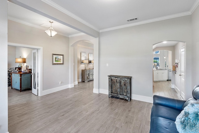 living area featuring visible vents, arched walkways, light wood-style floors, and ornamental molding